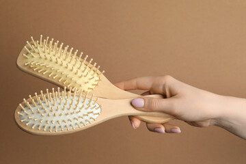 Woman with wooden brushes on beige background, closeup