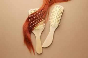 Fototapeta premium Wooden brushes and lock of hair on beige background, flat lay