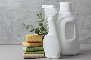 Eco-friendly cleaning products, supplies and eucalyptus branches on grey table