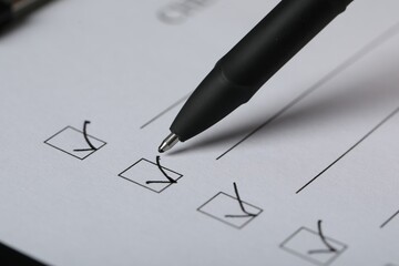 Paper sheet with checkboxes and pen, closeup