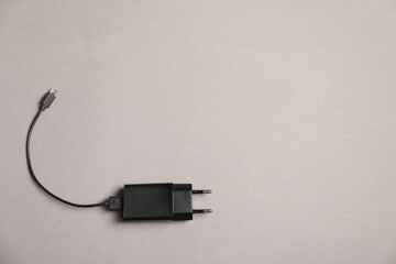 USB power adapter with charge cable on grey background, top view. Space for text