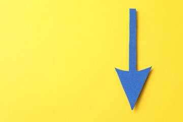 One blue arrow on yellow background, top view. Space for text