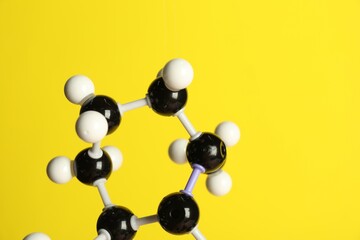 Molecule of retinol (vitamin A) on yellow background, closeup and space for text. Chemical model