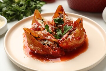 Delicious conchiglie pasta with ricotta cheese, tomato sauce and parsley on light table, closeup