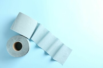 Color toilet paper rolls on light blue background, top view. Space for text