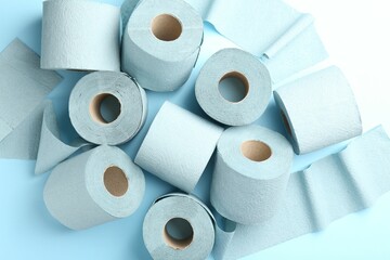 Color toilet paper rolls on light blue background, top view