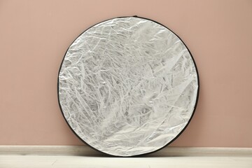 One light reflector near beige wall indoors. Photo studio equipment
