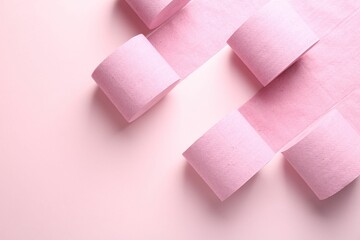 Color toilet paper rolls on light pink background, flat lay. Space for text