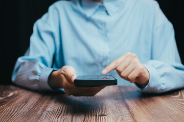 Woman Using Smartphone While Sitting at Wooden Table in Blue Shirt, Business concept