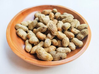 High angle view of boiled peanuts (Arachis Hypogaea L.) in a wooden bowl on a white background.