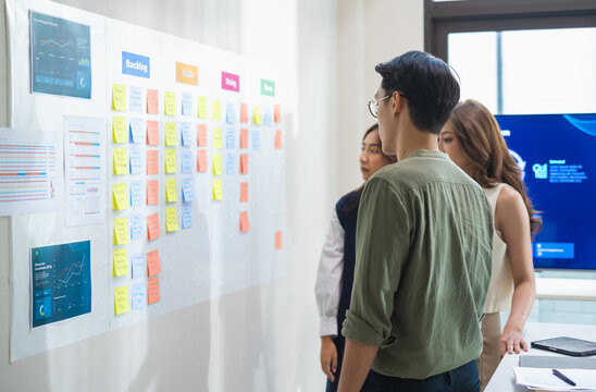 brainstorming session, using sticky notes on a task board (kanban) to organize ideas and workflow in a modern office