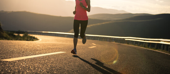 Woman runner running in sunset mountain road
