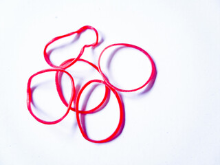 Fototapeta premium Close-up red rubber bands against a plain white background. The rubber bands are scattered randomly, with no apparent pattern or arrangement.
