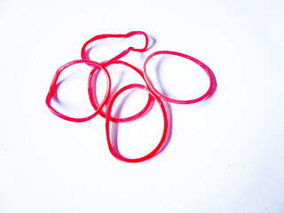 Fototapeta premium Close-up red rubber bands against a plain white background. The rubber bands are scattered randomly, with no apparent pattern or arrangement.