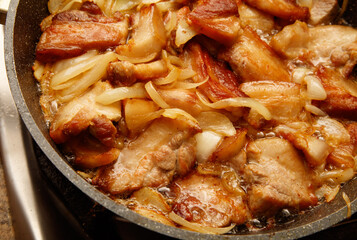 A pan of meat and onions is cooking on a stove