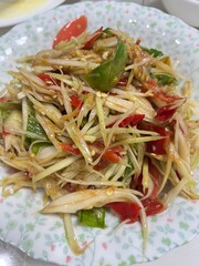 Exotic Papaya Salad: A close-up view of a vibrant papaya salad with crisp, shredded green papaya, juicy tomatoes, spicy chili, and aromatic herbs.