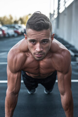 Obraz premium male athlete doing wall sit exercise in parking lot
