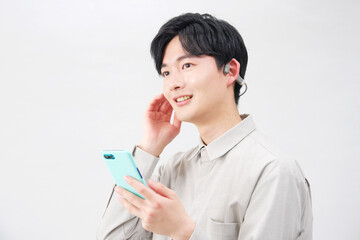 骨伝導イヤホンをつけて音楽を聴く20代男性　白背景
