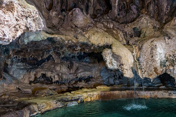 This captivating image reveals a mystical cave featuring impressive stalactites alongside clear turquoise waters that evoke secrets of the subterranean world.