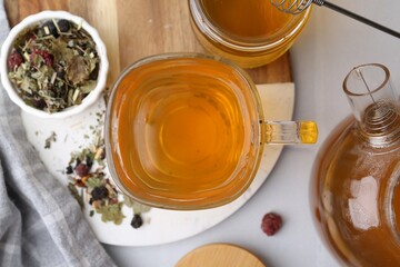 Delicious herbal tea with honey and dry leaves on white table, flat lay