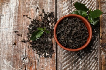 Dried and fresh tea leaves on wooden table, top view