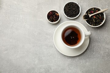 Aromatic tea and dried leaves on grey table, flat lay. Space for text