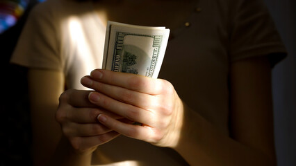 A person is counting bills in a dimly lit room. The warm light creates a cozy atmosphere, highlighting the focus on the currency in hand during daylight hours.