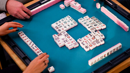 A mahjong table with an active game and the hands of a participant in the game. Fragment of the game. © Volha