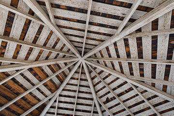This captivating image features a detailed wooden ceiling with a unique geometric pattern, illuminated by natural light, showcasing craftsmanship and architectural beauty.
