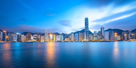 Naklejka premium wide angle shot of vibrant city skyline at dusk with glowing lights reflecting on water