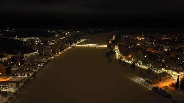 Drone flying toward the Ylisoutajan silta bridge, winter night in Joensuu, Finland