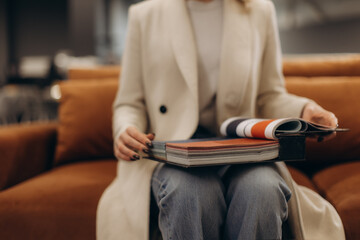 Woman Browsing a Catalog While Sitting on a Comfortable Sofa