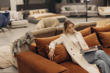 Obraz premium Woman Relaxing on a Modern Sofa in a Comfortable and Stylish Home Setting