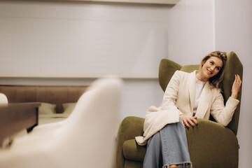 Smiling Woman Relaxing on an Olive Colored Sofa in a Cozy Room