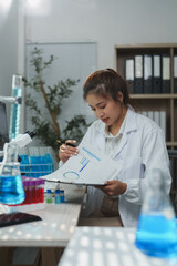 Young scientist wearing lab coat examining research data on charts and graphs while working at desk...