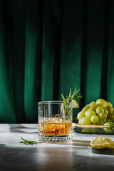a glass of whiskey decorated with lemon and rosemary