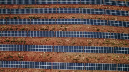 A lot of solar panels lie in straight lines on a deserted land, a bird's-eye view from a drone
