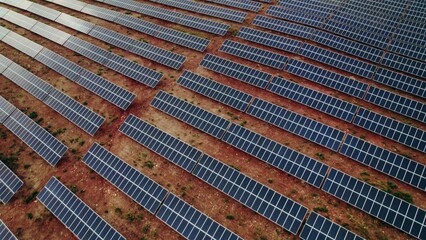 A lot of solar panels lie in straight lines on a deserted land, a bird's-eye view from a drone