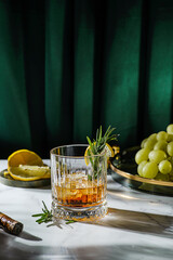 a glass of whiskey decorated with lemon and rosemary