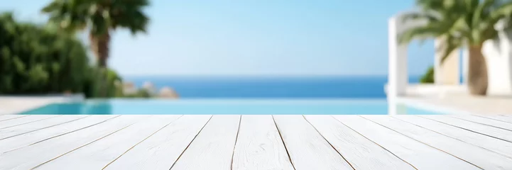 Leerer weißer Holztisch mit unscharfem Blick auf luxuriösem Pool, Palmen und Meer, Produktpräsentation für Reisen und Luxus Hotels © Jennifer