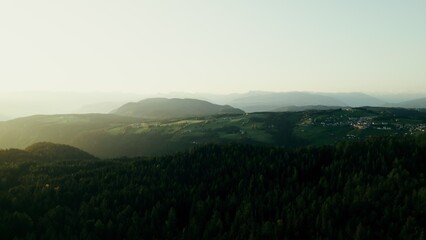 A high-altitude valley with a settlement on top of a mountain at sunset on a summer day, a bird's-eye view from a drone