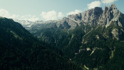 Fototapeta premium Drone view of a high-altitude valley with rocky peaks and slopes overgrown with spruce forest