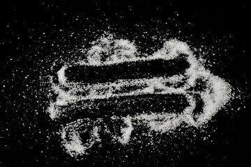 White crystals of table salt are scattered on a black background.