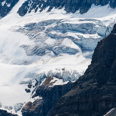 A stunning view of a glacier against towering peaks, with intricate patterns in the ice and rock that showcase nature's grandeur and the power of erosion over time.