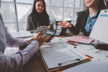 Businesswomen analyzing financial reports while calculating figures and discussing corporate strategy in a modern office setting, collaborating on data-driven decisions and planning for success