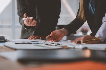 Business team collaborating in a modern office, reviewing documents, pointing with pens, and discussing strategies during a corporate meeting focused on project planning and analysis