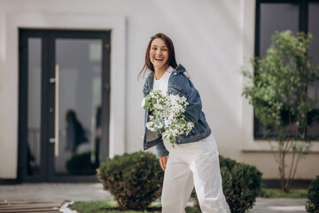 Fototapeta premium An adult young beautiful female model walks around the city with a bouquet of blooming apple trees