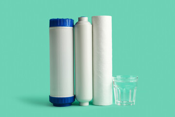 Glass of liquid and water filter cartridges on green background