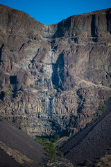 An eroded canyon showcases stunning geological formations and layers of rich earthy tones,...