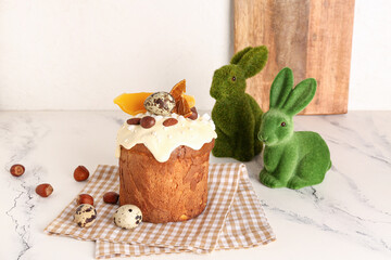 Easter cake with herbal rabbit figures and quail eggs on white grunge table near light wall